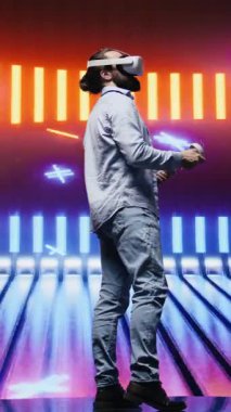 Dikey Video Havalı modern adam sanal gerçeklik gözlükleriyle sanatsal titreşimler sergiliyor, eğlence için siber punk atmosferinde renkli neon ışıklarla çevrili. Gece hayatı minimalizmi. Kamera.