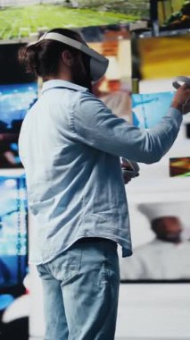 Dikey Video Genç rahat adam sosyal medya platformları için yapay zeka bağlantısı gösteren 3 boyutlu kullanıcı arayüzü tasarımı için VR gözlük kullanıyor. Dijital dünyada eğlence üzerine çalışan erkek sosyal ağ kullanıcısı