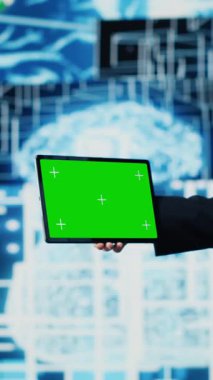 Dikey Video İş AI uzmanı beyin animasyonunun yanındaki cihazda yeşil ekran tutuyor ve sinirsel ağ sisteminin uygulanmasını sağlıyor. Algoritmaları ve kodlama araçlarını analiz eden genç bir uzman. Kamera A.