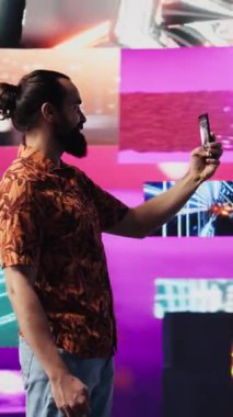 Dikey Video Genç Erkek Oyuncu, kendini özçekim ve videolarla kaygısız hissederek, siber punk görsel sanatı altında cep telefonuyla fotoğraf çekiyor. Eğlenceli insan gece hayatı titreşimlerini sever. Kamera B.