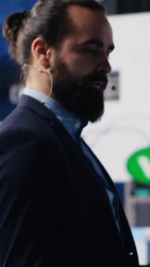 Vertical Video Visionary iş dünyası lideri kalabalık bir konuşma etkinliğinde veri ve grafikler kullanarak ayrıntılı bir iş sunumu yapıyor. CEO uzmanı olarak dinleyen izleyiciler büyüme ve başarı anlayışını paylaşıyor