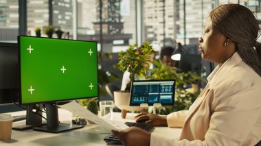 Çalışan proje görevlerini tamamlamak için izole ekran PC görüntüsünü kullanıyor. İş yerindeki Afrikalı Amerikalı ofis görevlisi model bilgisayar monitörü ve B kamerasıyla ilgili veri istatistikleri okuyor.