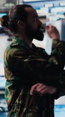 Dikey video erkek ordu subayı, dijital teknolojisi olan bir komuta merkezinden modern savaş stratejisi için uydu istihbaratını takip ediyor. Etkin işlemlerde iletişimi güvene al
