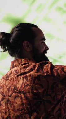 Dikey Video Genç kaygısız adam, modern DJ kültürünün, medya etkisinin ve dijital sanatın performansını temsil eden eğlenceli neon ışıklar ve ritimlerle çevrili selfie ve videolar çeker.