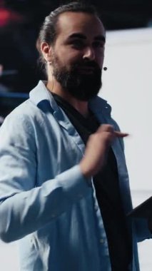 Dikey Video Erkek sunucusu izleyicilere markalaşma stratejisi ve sosyal eğilimler hakkında iletişim kuruyor, sunum sırasında iletişim ve küresel erişime yardımcı olmak için mikrofon kullanıyor. Kamera A.