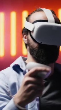 Dikey Video Sanatçısı genç adam, neon ışıklar ve siber punk parıltısı altında sokak stilini modern moda ve teknolojiyle harmanlayarak estetik görsellerle dolu serin bir ortama daldı.