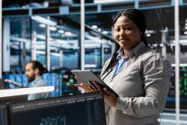 Sunucu teknolojisini güncellemek için tablet kullanan gülümseyen veri merkezi programcısının portresi, yazılım araçları kullanarak donanımı yapılandırmak. Donanım analizlerini aygıt kullanarak inceleyen mutlu sunucu tarım işçisi