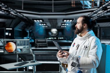 Mars 'a doğru navigasyon koordinatlarını doğrulamak için tablet kullanarak yörünge istasyonunda kozmonot. Yörünge istasyonunda çalışan adam görev günlüklerini analiz ediyor ve Mars yüzey araştırması yapıyor.