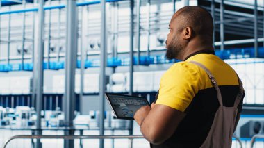 Endüstri 4.0 endüstriyel fabrika uzmanı tablet üzerindeki CAD programını kullanarak yeni robotik makineler tasarlıyor. Afrika kökenli Amerikalı bir adam akıllı fabrikada otomasyon ekipmanları için cihaz kullanıyor. Kamera A