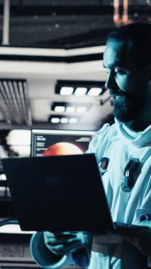 Uzay istasyonunun dışındaki planlanmış operasyonlara çıkmadan önce kaskını takan dikey video astronotu iş arkadaşıyla yumruk tokuşturuyor. Kozmonot indikten sonra uzay gemisinden ayrılmaya hazırlanıyor.