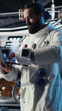 Uzay gemisinde tablet kullanan dikey video kozmonot insanoğlunun hayatta kalma seferi sırasında güvenlik kontrolü yapıyor. Astronotlar uzay görevinde insan genleşmesi sırasında yaşam destek sistemlerini izliyorlar