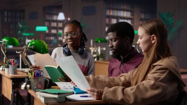 Üniversite öğrencileri kampüs kütüphanesinde uluslararası işletme yönetimi ve yönetimine odaklanarak başlangıç projesinde işbirliği yapıyorlar. Akademik diplomaları için çok çalışıyorlar. Kamera A.