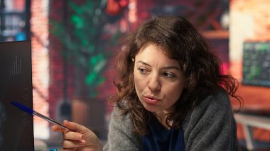 Kadın ve erkek bilgisayar kurulumunda iş konferansı bilgilerini izliyor, online portföydeki istatistiklere bakıyor. Analistler iş sunumunu gözden geçiriyorlar. Kamera B.