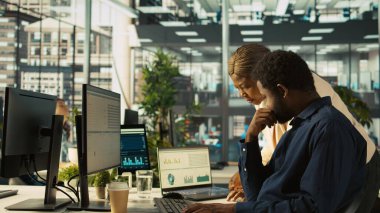 Ofisteki çalışanlar dizüstü bilgisayardan yöneticiye gelir rakamlarını gösteriyor. İşi bitirdikten sonra şirket istatistiksel numaralarını yöneticiye sunan muhasebeci, kamera B