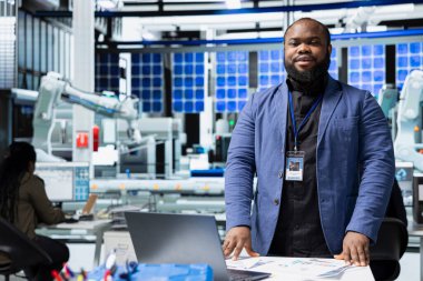 Bir güneş paneli fabrikasında çalışan siyah sanayi mühendisi sistem performansını değerlendiriyor ve verimlilik ve işyeri güvenliğinin izlenmesinde önemli bir rol oynuyor. Fotovoltaikle yenilenebilir güç.