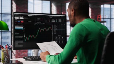 Gündüz işlemcisi iyi performans gösterebilecek hisse senedi almak ve değeri düşebilecek hisse senedi satmak için bilgisayar kullanıyor. Eski tüccar bilgisayar masasında hisse senedi portföy sayfalarına göz atıyor. Kamera A.