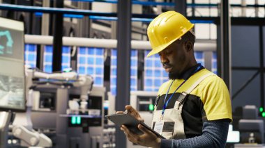 Güneş panelleri fabrikasındaki teknisyen, IoT sensör verilerini analiz etmek için tablet kullanıyor. Fotovoltaik sistemlerin işlevsel güvenilirliğini yöneten sanayi 4.0 bitki uzmanı, kamera B