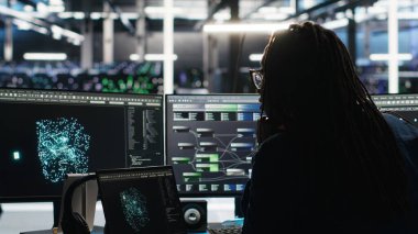 Sunucu merkezi teknisyeni, sistem sağlığını optimize etmek için bilgisayardaki yapay zeka görselleştirme bilgilerini kullanarak ofise geliyor. Veri merkezi bilişim uzmanı, dişli sorunlarını analiz etmek için bilgisayar düğümü ağacı yazılımı kullanıyor, kamera B