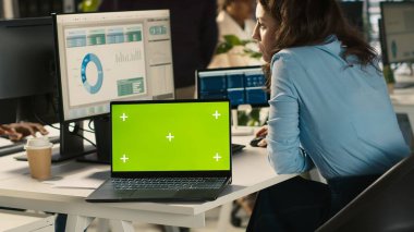 Ofis masasındaki yeşil ekran dizüstü bilgisayarda çalışan kurgu belgelerinin yanında. Veri tablolarını analiz eden, istatistiksel bilgileri yorumlayan, kamera A 'nın yanındaki defter.