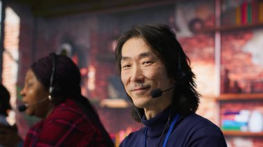 Çağrı merkezinde teknik destek uzmanı. Kulaklık, bilgisayar çalışma istasyonu ve kamera A kullanılarak adım adım müşteri bağlantıları sorunu çözülüyor.