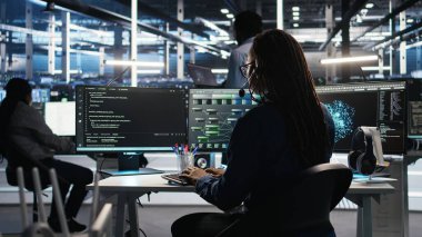 Veri merkezi uzmanı düğüm ağacı arayüzünü inceleyerek teknik destek sağlıyor. Sunucu odası teknisyeni iş arkadaşlarıyla mikrofonla konuşuyor, görsel programlama yazılımı kullanıyor, kamera A
