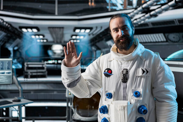 Astronaut waves hand during video call with command center on Earth while stationed aboard spacecraft. Cosmonaut saluting researchers, doing mission update during communication link to ground control