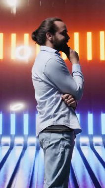 Neon ışıklı fütüristik ortamda poz veren dikey video modası genç kişi, gençlik kültürünün, yaratıcılığın ve minimalizmin özünü retro dijital bükülme ve güçlü sokak kıyafetleriyle yakalıyor.