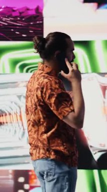 Vertical Video Artistic çalışanı ve DJ, canlı neon ışıklar, müzik kültürü, görseller ve sosyal medya veya yayın için kentsel ortam ile gece hayatı titreşimi altında telefon görüşmelerine cevap verir. Havalı yaratıcı adam.