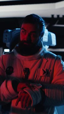 Uzay istasyonunda miğfer tutan gülümseyen astronotun dikey video görüntüsü. Gezegen görevine hazırlanıyor. Mutlu yıldız gemisi mürettebatı güneş sisteminde iniş prosedürlerine başlıyor.