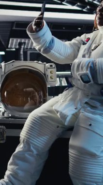 Dikey video astronotları uzay gemisinden çıkmadan önce izole ekran tabletindeki analizleri inceliyor. Gezegen A 'ya indikten sonra kroma anahtar cihazının parametrelerini doğrulayan kozmonotlar.