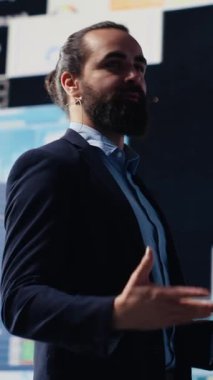 Dikey Video Motivasyon Konuşmacısı ve iş adamı katılımcı kalabalığa konuşma sunuyor. Uzman, görünür mali tablolarıyla yatırım, iş planlaması ve girişimciliği kapsıyor