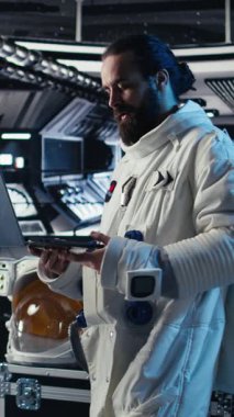 İnsanoğlunun hayatta kalma mücadelesi sırasında tablet kullanarak uzay gemisi donanımını ters çeviren dikey video. Uzay görevinde insan genleşmesi sırasında cihazdaki yıldız haritalarını inceleyen araştırmacı