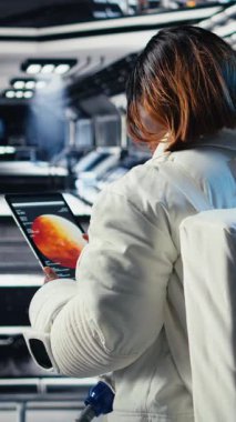 Yabancı gezegendeki yüzey görevini tamamladıktan sonra uzay istasyonunda miğfer tutan neşeli kadın astronotun dikey video portresi. Gülümseyen Afro-Amerikan kozmonot geri dönmeye hazırlanıyor.