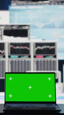 İşle ilgili bir ortamda, dizüstü bilgisayar finansal verilerle strateji planlamasına yardımcı olmak için yeşil ekran gösteriyor. Modern yapay zekayı ve üretkenliği temsil ediyor.