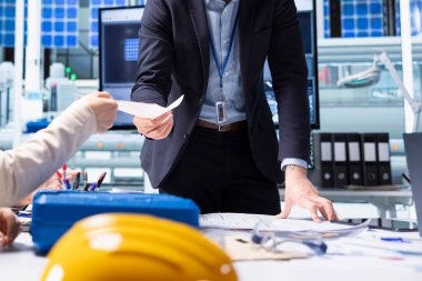 Hissedarlar araştırma ve geliştirme sürecinde endüstriyel üretim fırsatları ve teknolojik içgörülerin raporunu okuyorlar. Fabrika yöneticisi yatırımcılara belge dosyaları sunuyor