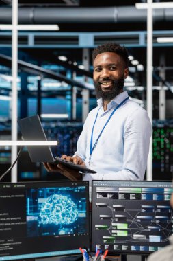 Sunucu merkezindeki neşeli adam yapay zekayı kullanarak bilgisayar gerektiren işleri yapıyor. Veri merkezindeki neşeli yönetici makine öğrenme iş yükleri için yapay zeka teknolojisi kullanır