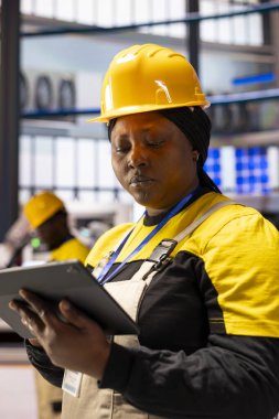 Endüstriyel üretim tesisinde kadın mühendis sistem performansını kontrol ediyor. Profesyonel kadın akıllı fabrikada otomasyon yazılım verilerini analiz ediyor, 4.0 üretim sektörünü denetliyor..