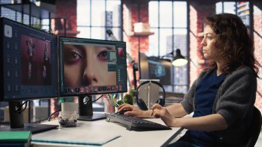 Ajans ofisindeki modern bir bilgisayar kurulumunda renk derecelendirme ve rötuş tekniği kullanarak fotoğraf düzenleyen genç bir fotoğrafçı. Dijital tasarımcı ve sanat fotoğrafçılığı için ideal bir çalışma alanı. Kamera A.