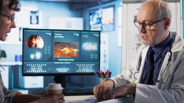 Uzman ve yaşlı kadın önleyici kanser ilacı ve sağlık farkındalığı için röntgen taramasını tartıştılar. Kanser uzmanı yaşlı bir hastaya tümör riskleri hakkında bilgi veriyor. Kamera A.