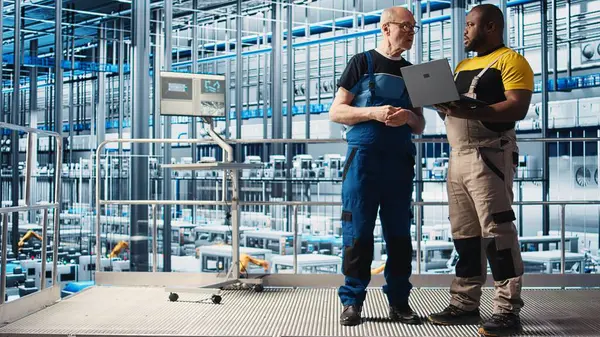 Kıdemli mühendis akıllı fabrikada stajyerlerle konuşuyor, veri topluyor ve analiz ediyor. Tecrübeli teknisyen, stajyerin takip yazılımını kullanmasına yardım ediyor. Endüstriyel tesiste sensörlerle donatılmış, kamera A