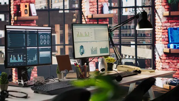 Ofis masasındaki bilgisayar monitörleri veri analizlerini ve performans çizelgelerini gösteriyor. Finansal ölçümler ve üretkenlik verilerini gösteren şirket çalışma alanındaki bilgisayar ekranları
