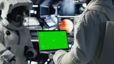 Astronotlar uzay gemisinden çıkmadan önce izole edilmiş ekrandaki analizleri inceliyor. Kozmonotlar gezegene indikten sonra kroma anahtar defteri üzerinde parametreleri doğrulayan kamera B