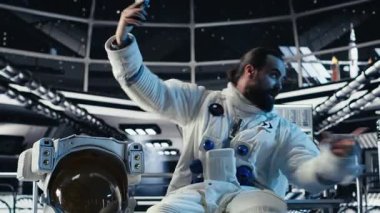 Astronot akıllı telefonuyla özçekim fotoğrafları çekiyor. Gezegen kolonileştirme görevi sırasında el hareketi yapıyor. Kozmik yolculuk sırasında cep telefonuyla fotoğraf çeken Yörünge İstasyonu mürettebatı, kamera B