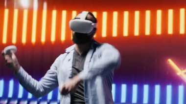 Havalı modern adam sanal gerçeklik gözlükleriyle, eğlence için siber punk atmosferinde renkli neon ışıklarla çevrili sanatsal titreşimler sergiliyor. Gece hayatı minimalizmi. Kamera A.