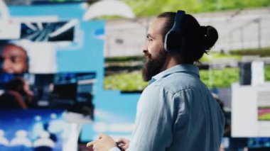 Kulaklıklı sıradan bir adam, iletişim ve çevrimiçi eğlencenin gücünü vurgulayarak sosyal medya görsellerine ve kullanıcı arayüzü unsurlarına hayran. Web dijitalleşmesi. Kamera A.