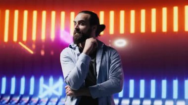 Neon ışıklı fütüristik ortamda poz veren trend genç insan, gençlik kültürünün, yaratıcılığın ve minimalizmin özünü retro dijital bükülme ve güçlü sokak giyimi etkisiyle yakalıyor. Kamera A.