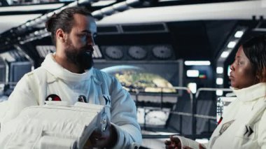 Astronot, uzay istasyonu dışındaki planlanmış operasyonlara çıkmadan önce kaskını takıyor ve meslektaşıyla yumruk tokuşturuyor. Kozmonot gezegene indikten sonra yıldız gemisinden ayrılmaya hazırlanıyor, Kamera B