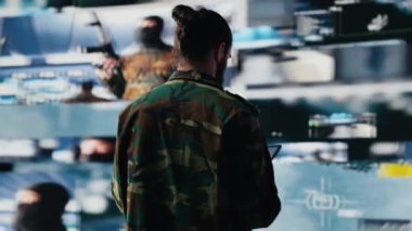 Silahlı kuvvetler subayı, savaş planlaması için bilgi toplamak amacıyla İHA ve uydu görüntülerini izliyor. Görev kontrol ve siber savunma yoluyla küresel operasyonları güvence altına almak. Kamera A.