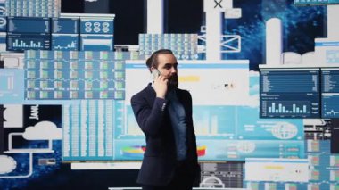 Profesyonel işadamı, şirketin performansını ve sezgilerini değerlendirmek için KPI metrikleriyle çevrili bir telefona cevap veriyor. İşini geliştirmek için uzaktan iletişimi kullanıyor, büyüklük. Kamera B.