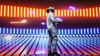 Havalı modern adam sanal gerçeklik gözlükleriyle, eğlence için siber punk atmosferinde renkli neon ışıklarla çevrili sanatsal titreşimler sergiliyor. Gece hayatı minimalizmi. Kamera B.